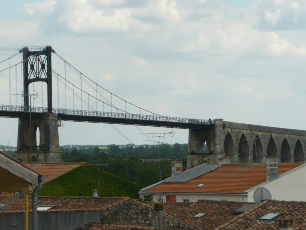 L’image actuelle n’a pas de texte alternatif. Le nom du fichier est : Pont_suspendu_au-dessus_des_toits_de_Tonnay-Charente.jpg